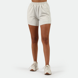 a fit woman wearing short marl light grey with shoes  white ,plus the background is light grey 