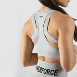 A person wearing a gray sports bra and matching leggings is shown from the back. The outfit has a racerback design and the word WINNERFORCE printed on the leggings. The background is plain white.