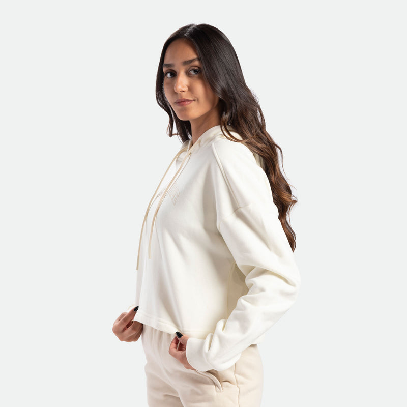 a fit woman stand at right  and wearing hoodie marshmallow with pants beige 
