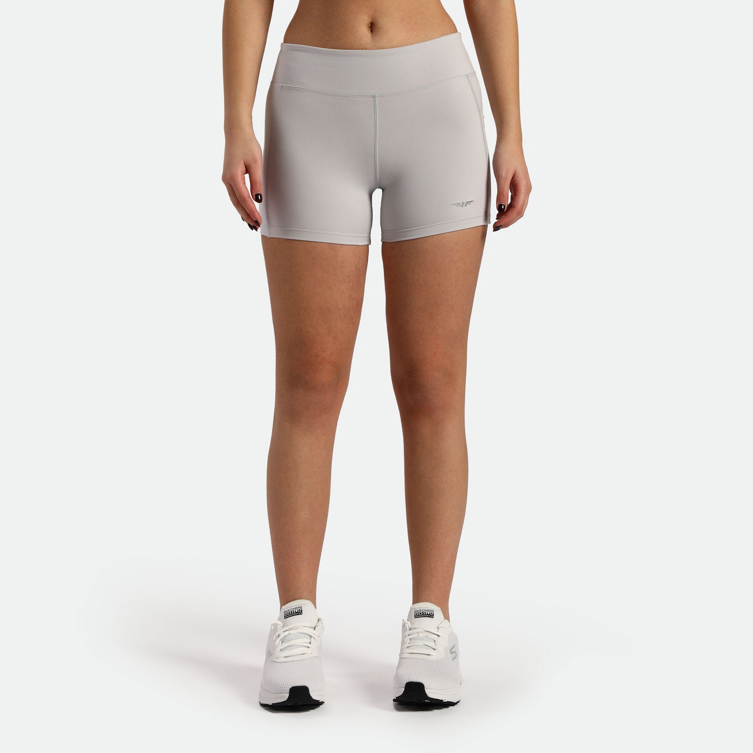 a fit woman wearing short grey with shoes white ,plus the background is light grey 