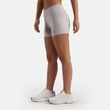 a fit woman stand at right and wearing short grey  with shoes white ,plus the background is light grey 