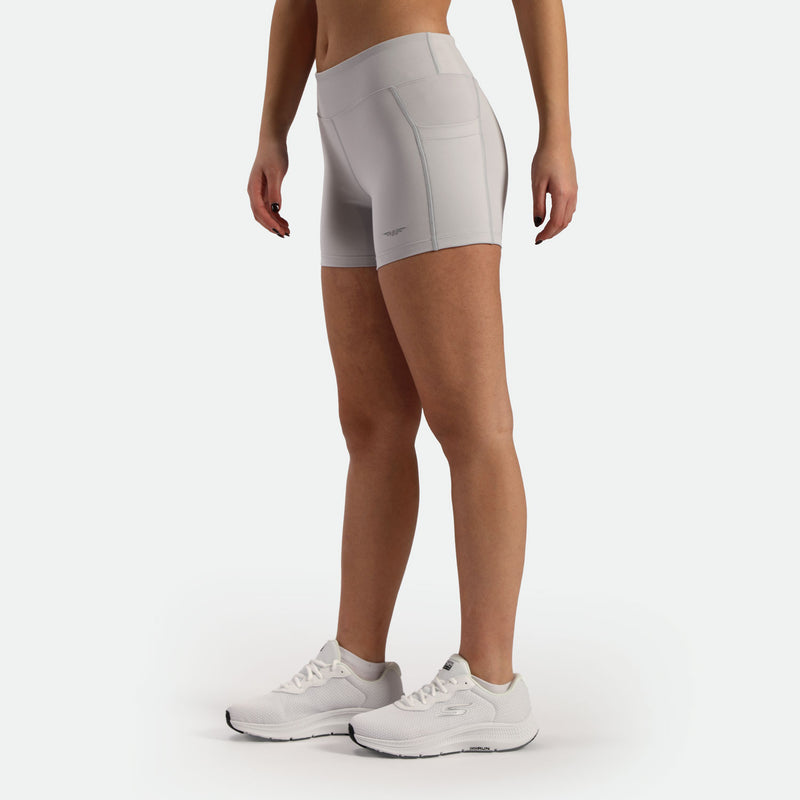 a fit woman stand at right and wearing short grey  with shoes white ,plus the background is light grey 
