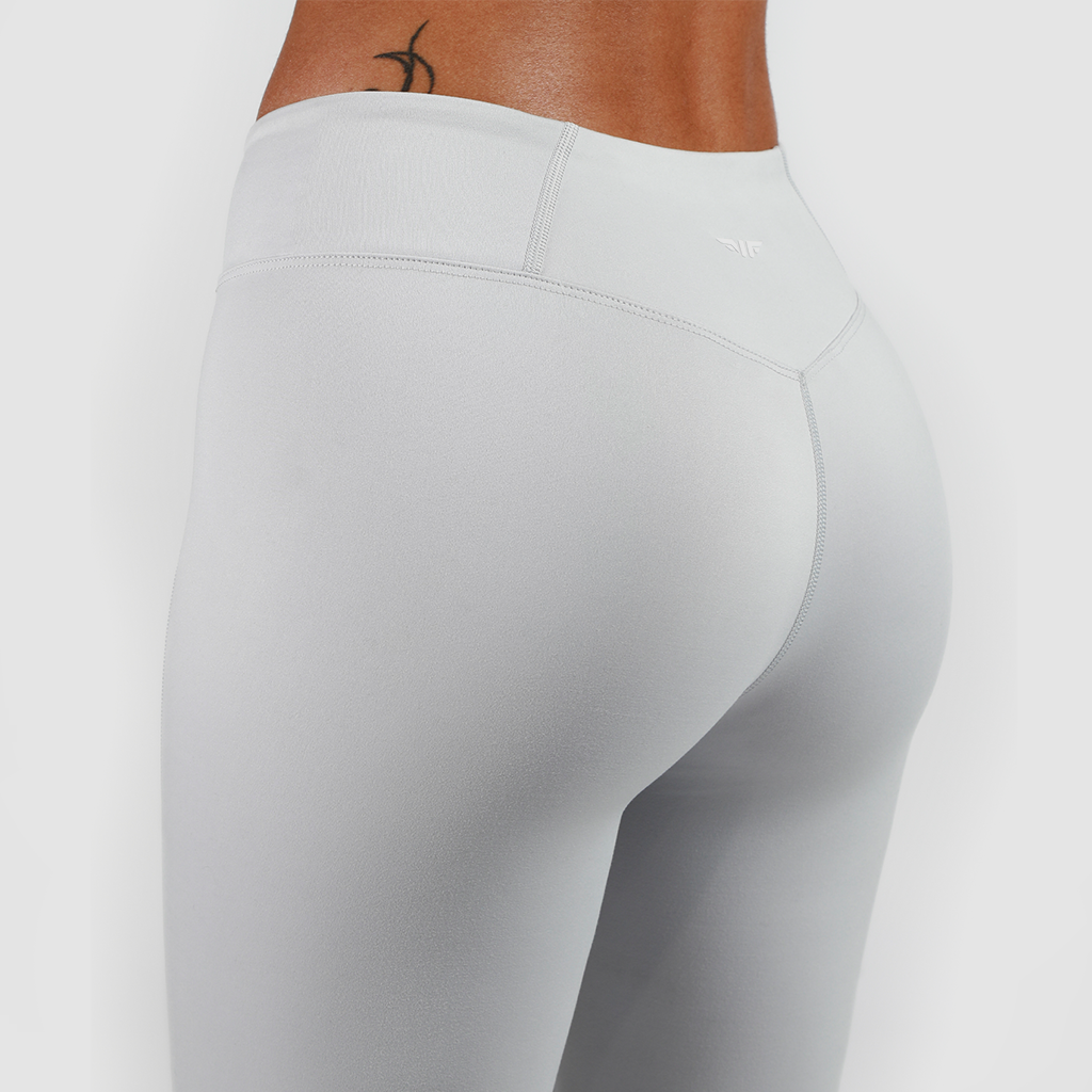 a back view for woman wearing legging grey with background is light grey 