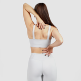 a back view for woman wearing matching grey bra and legging ,plus logo and background light grey