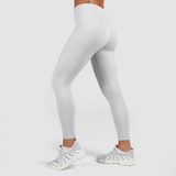 a fit woman stand at right and wearing legging grey with shoes white ,plus the background is light grey 