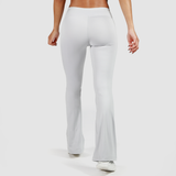 a back view for woman wearing  flared legging  and shoes white ,the background is light grey 