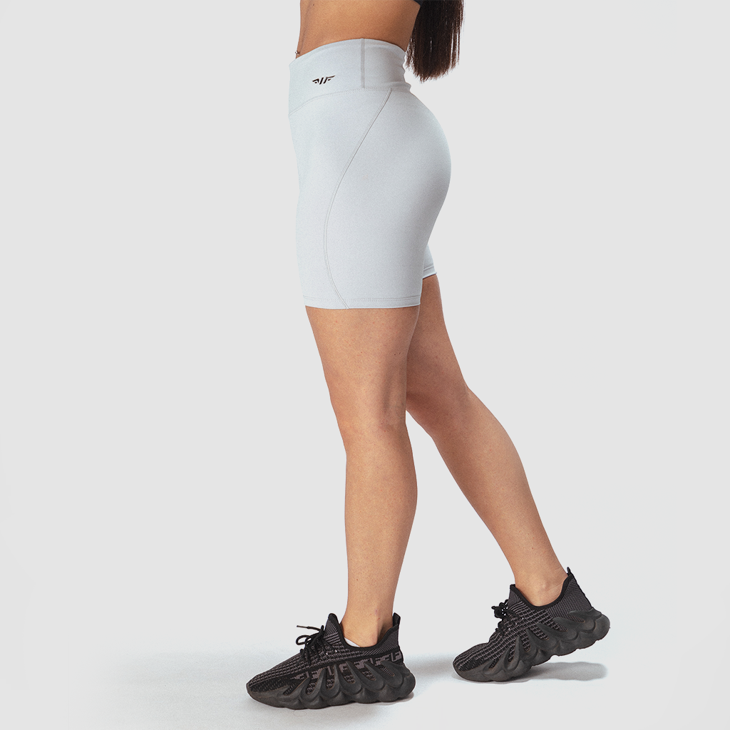 a fit woman stand at right and wearing short grey with logo and sneakers  black 
