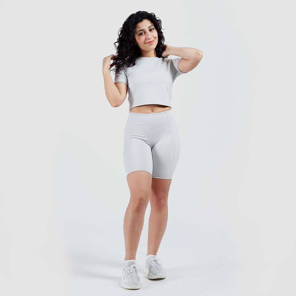 a fit woman wearing matching set grey  crop top and short with sneakers 