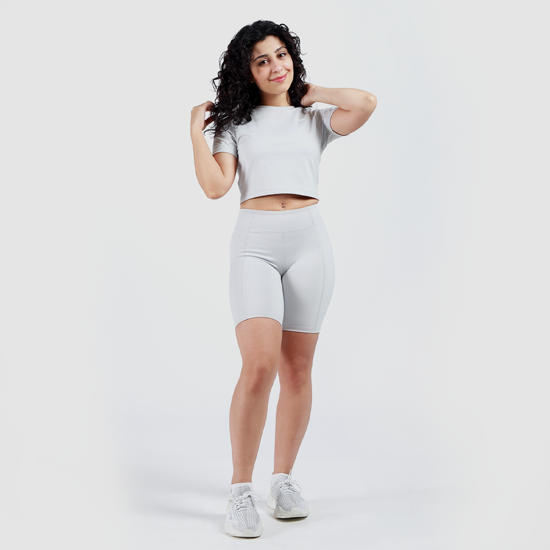 a fit woman wearing matching set grey  crop top and short with sneakers 