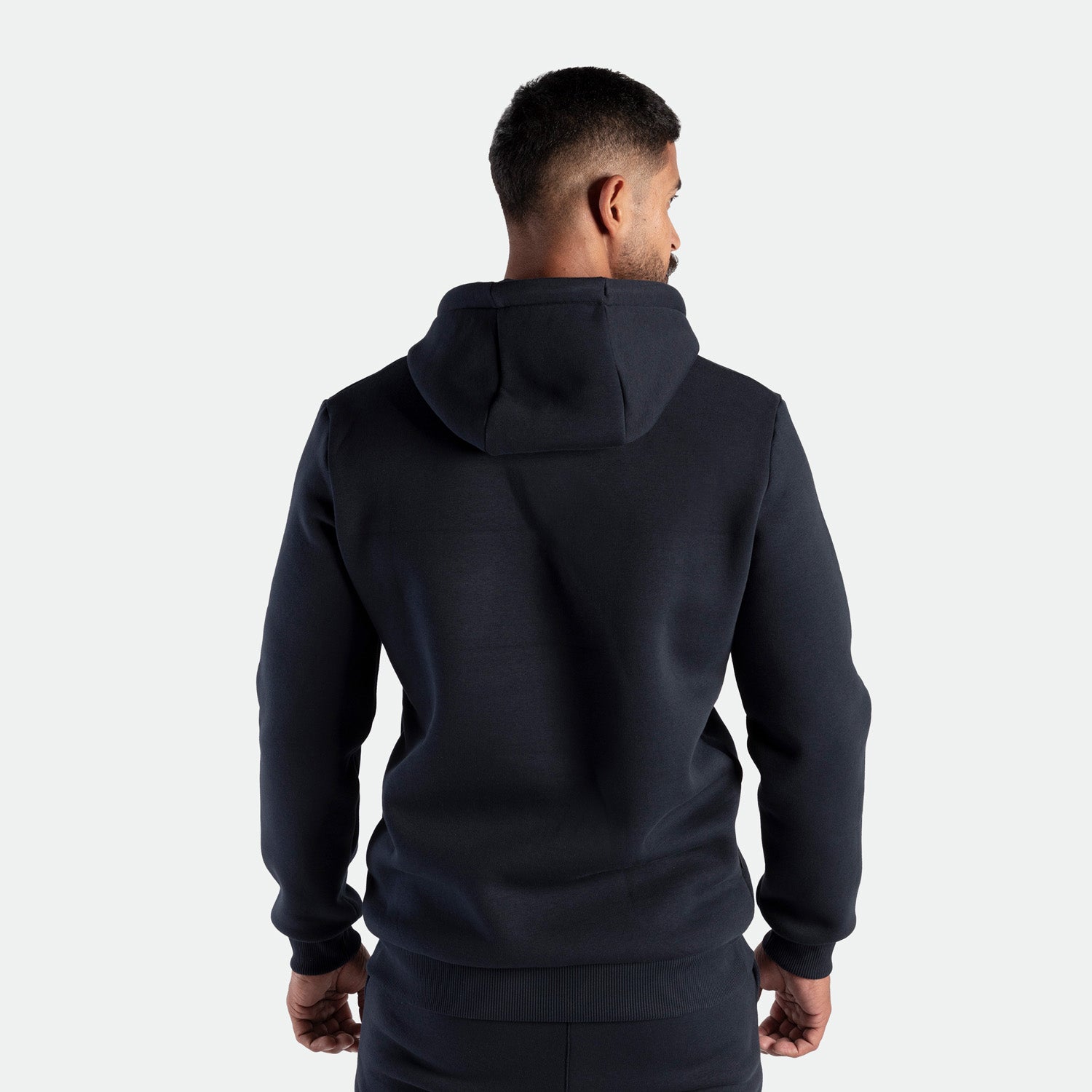 Person wearing a black hoodie from the back on a white background