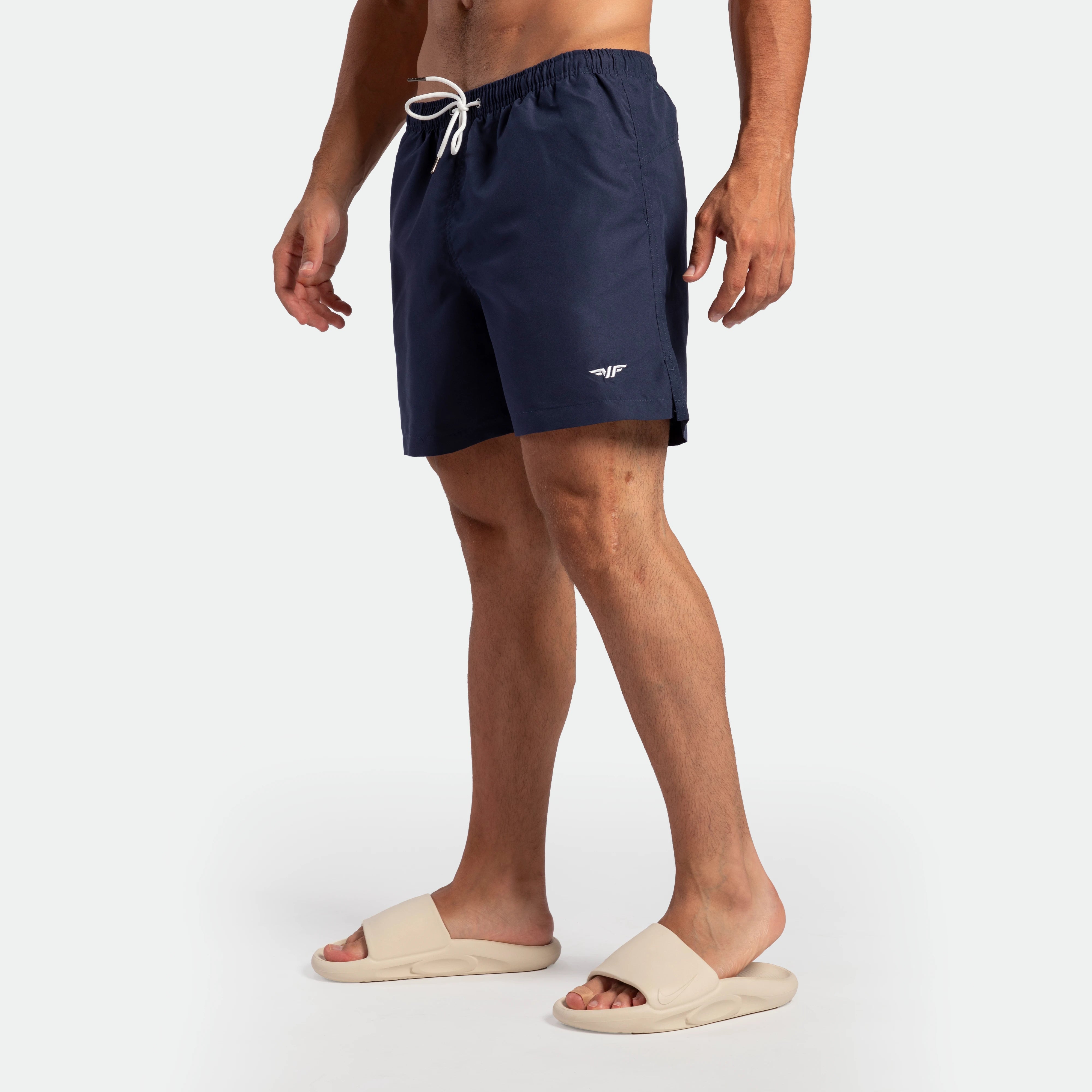 a fit man stand at right and wearing short  navy blue 