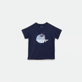 Navy blue short-sleeved t-shirt featuring a graphic of an astronaut floating in space with stars around, set against a circular blue background. The astronaut is positioned above a stylized wing logo.