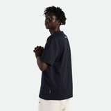 a fit man stand at right and wearing t-shirt  black with pants beige 