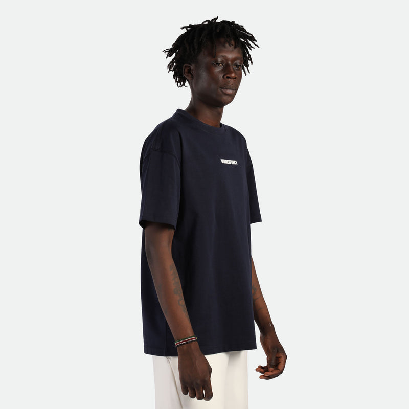 a fit man stand at right  and wearing t-shirt black with pants beige 