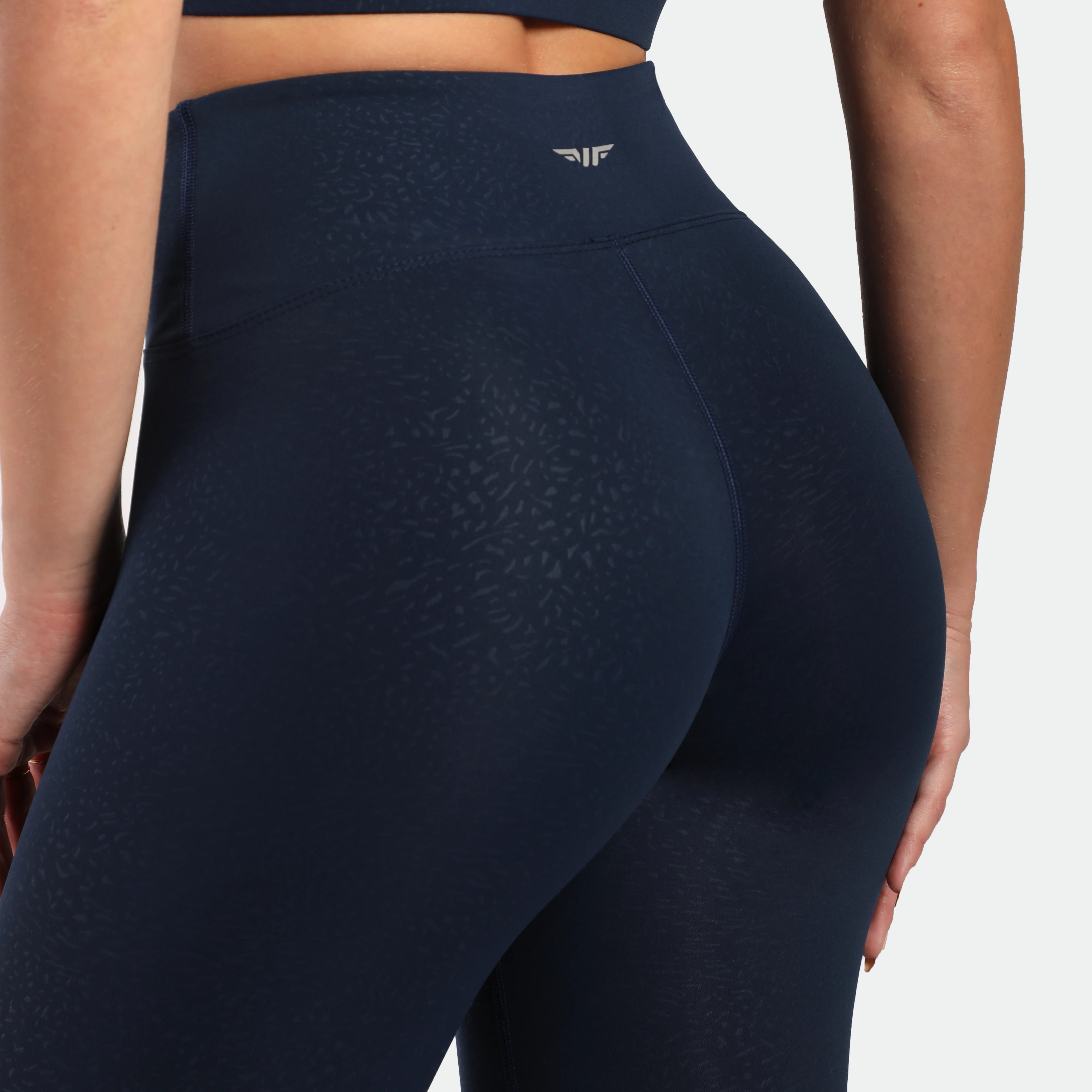 close up view for fit woman wearing legging navy blue terrazzo plus the logo in half  