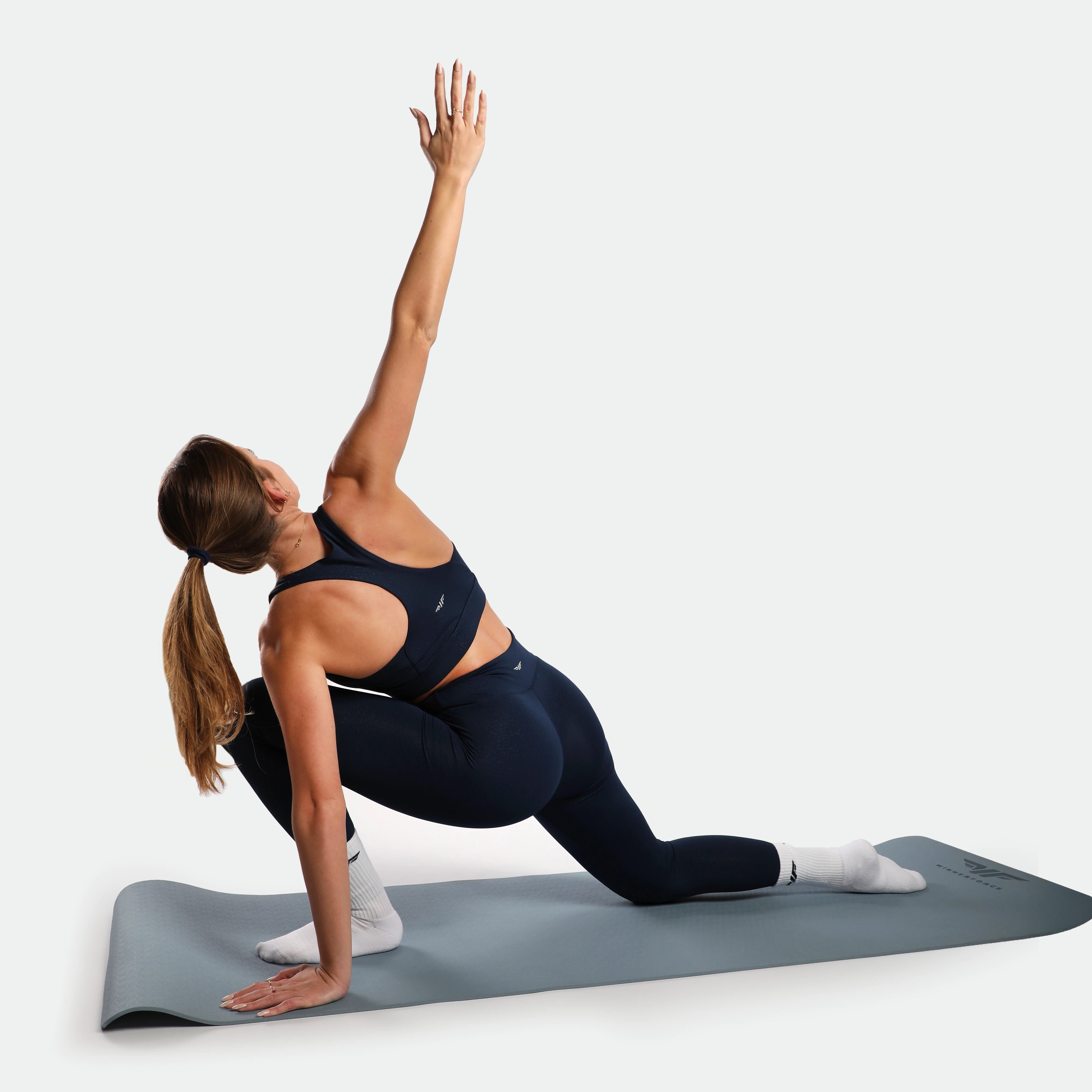 Woman practicing yoga on a mat with a white background