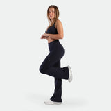 a fit woman stand at right with pose and wearing matching set navy ,bra and legging ,plus the shoes white 