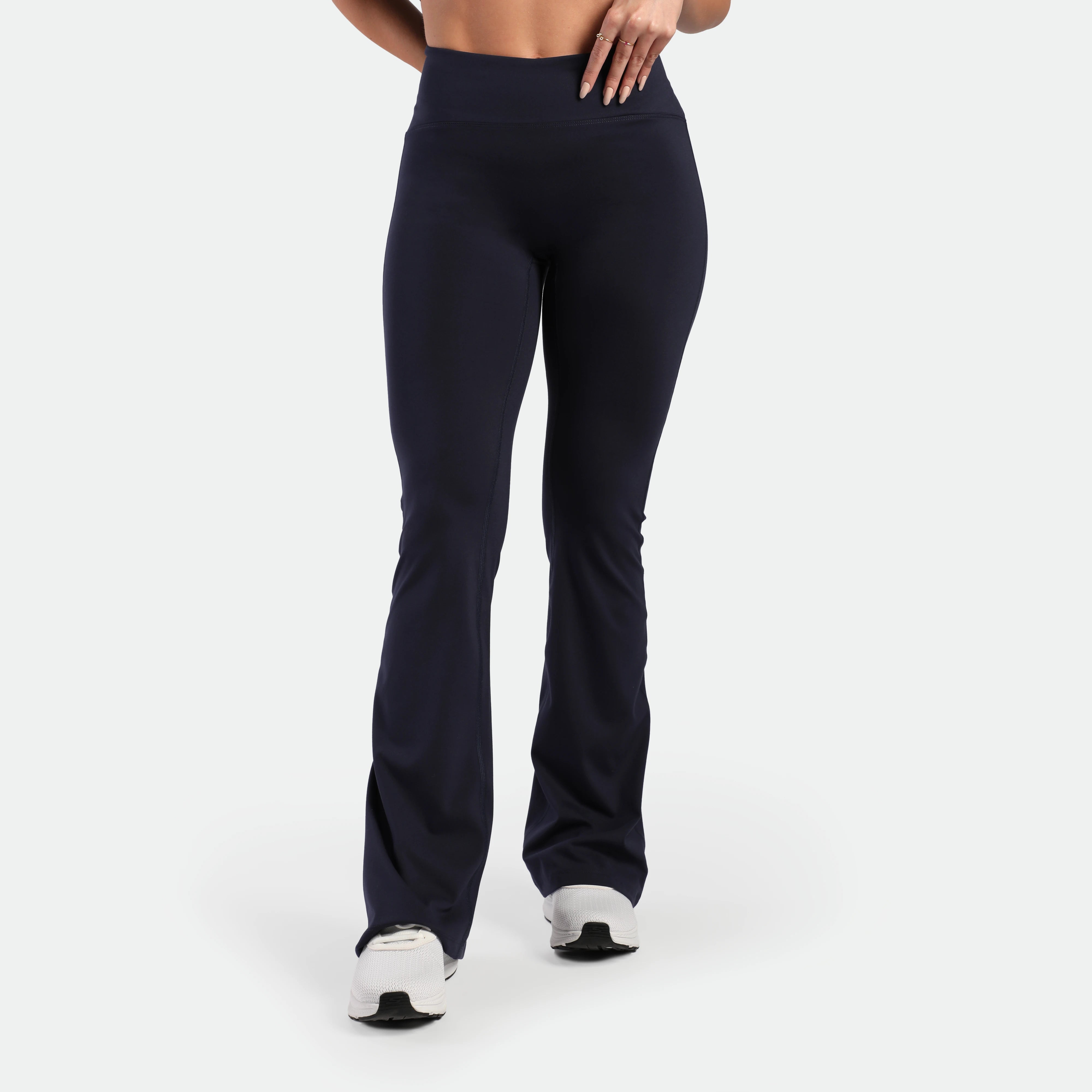 a fit woman wearing flared legging navy with shoes white 