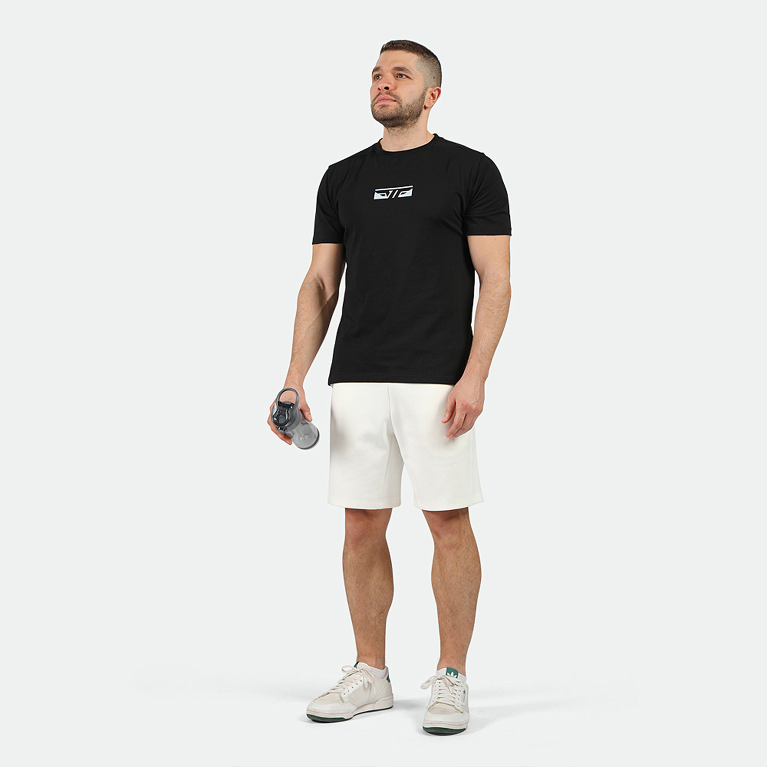 a fit man  wearing  t-shirt black  with short off white ,plus the sneakers 