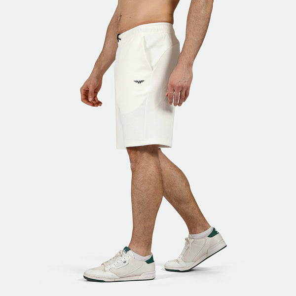 a fit man stand at  right and wearing short white with logo and sneakers 