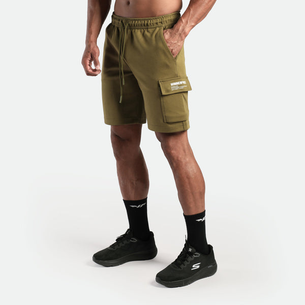 a fit man stand at right and wearing short olive drop with socks and shoes black 