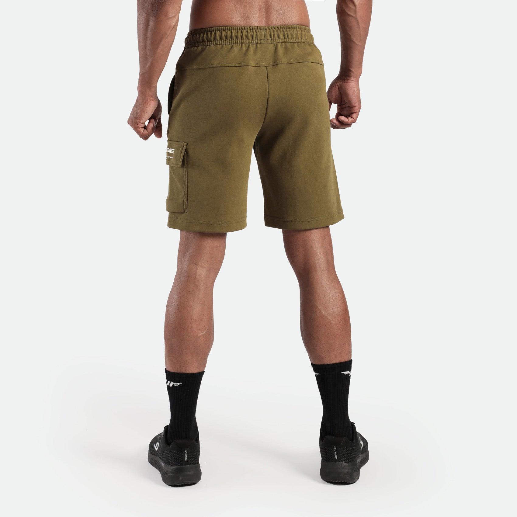 a fit man stand at right and wearing short olive drop with socks black and shoes black 