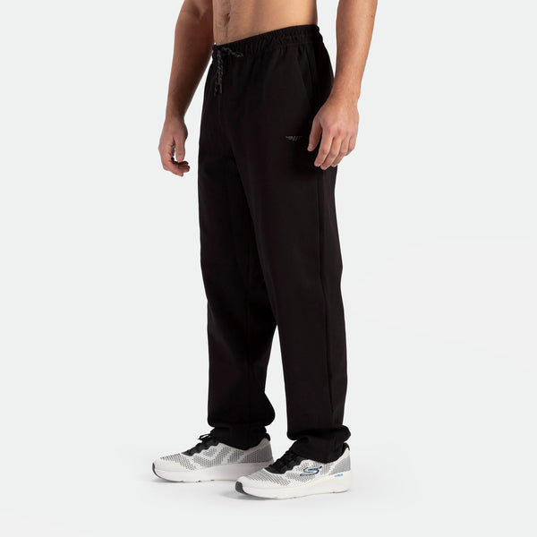 a fit  man stand at right and wearing pants black with shoes 
