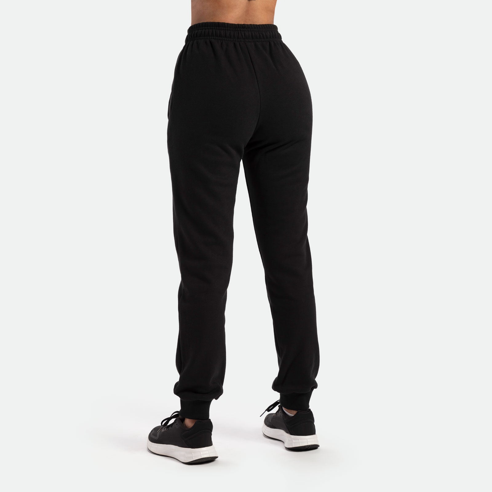 a back view for woman wearing  jogger pants with black shoes athletic, plus the background is light grey  