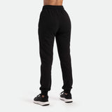 a back view for woman wearing  jogger pants with black shoes athletic, plus the background is light grey  
