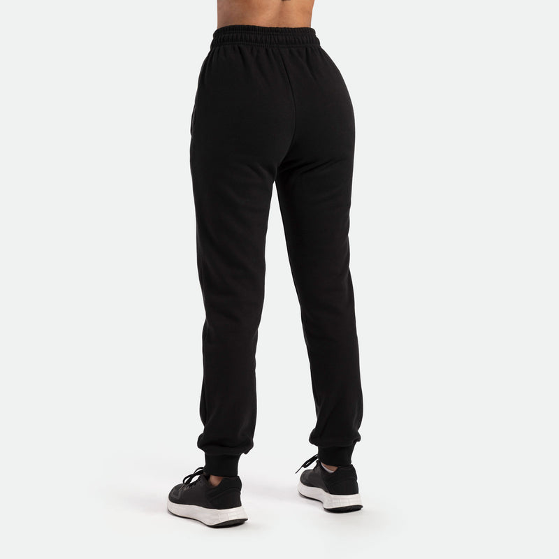 a back view for woman wearing  jogger pants with black shoes athletic, plus the background is light grey  