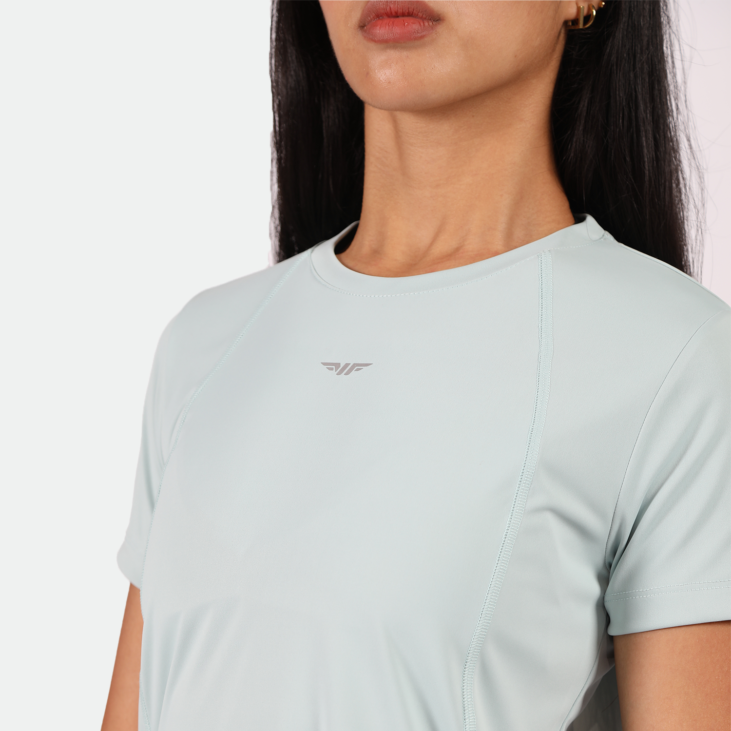 close up view for fit woman wearing t-shirt pastel blue with logo ,plus the background is light grey 