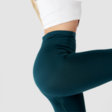 a  fit woman stand with pose , 
 she wearing bra white with legging green ,the background is light grey 