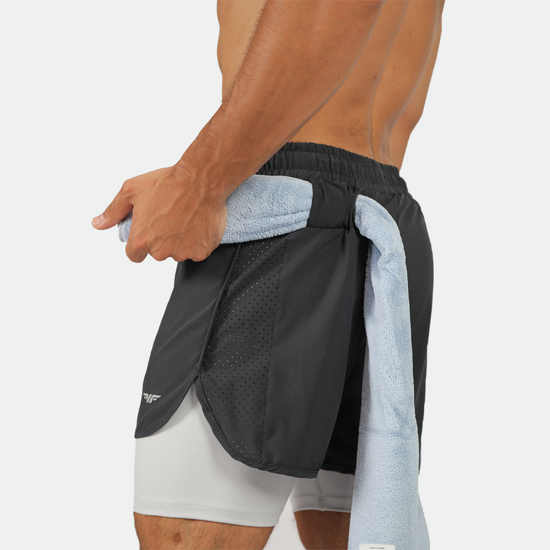 Shirtless man in athletic shorts with a towel tucked at waist. The focus is on the side view, displaying the textured fabric and lean physique.