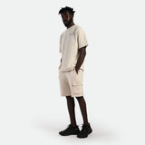 a fit man wearing matching set t-shirt and short light beige ,plus shoes black 