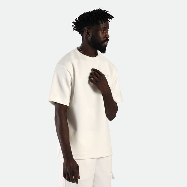 a fit man  wearing matching set t-shirt 
 off white with short beige 