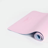 A rolled pink yoga mat with a smooth surface, partially unrolled on a plain white background. The mood is calm and inviting for exercise.