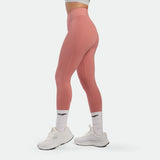 Person wearing pink leggings and white sneakers on a light gray background