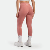 Person wearing pink leggings and white sneakers on a light gray background