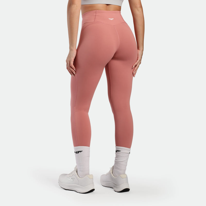 Person wearing pink leggings and white sneakers on a light gray background