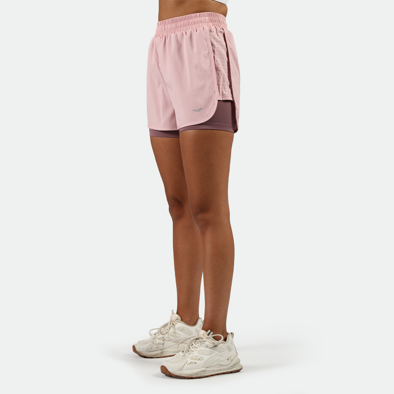 a fit woman wearing pink nectar short 2in 1  and shoes white ,plus the background is light grey 