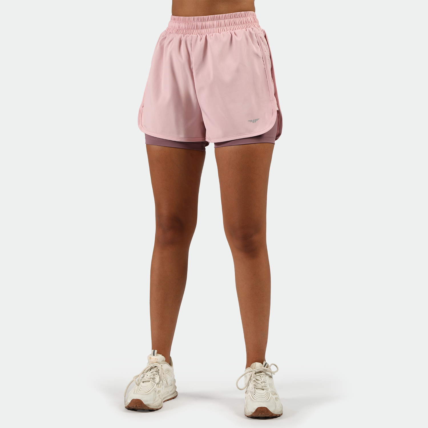 a fit woman wearing pink nectar short 2 in 1 with shoes white ,plus the background is light grey   