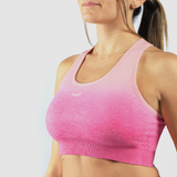  a woman fit wearing bra sport pink with logo white ,plus the background  is light grey 