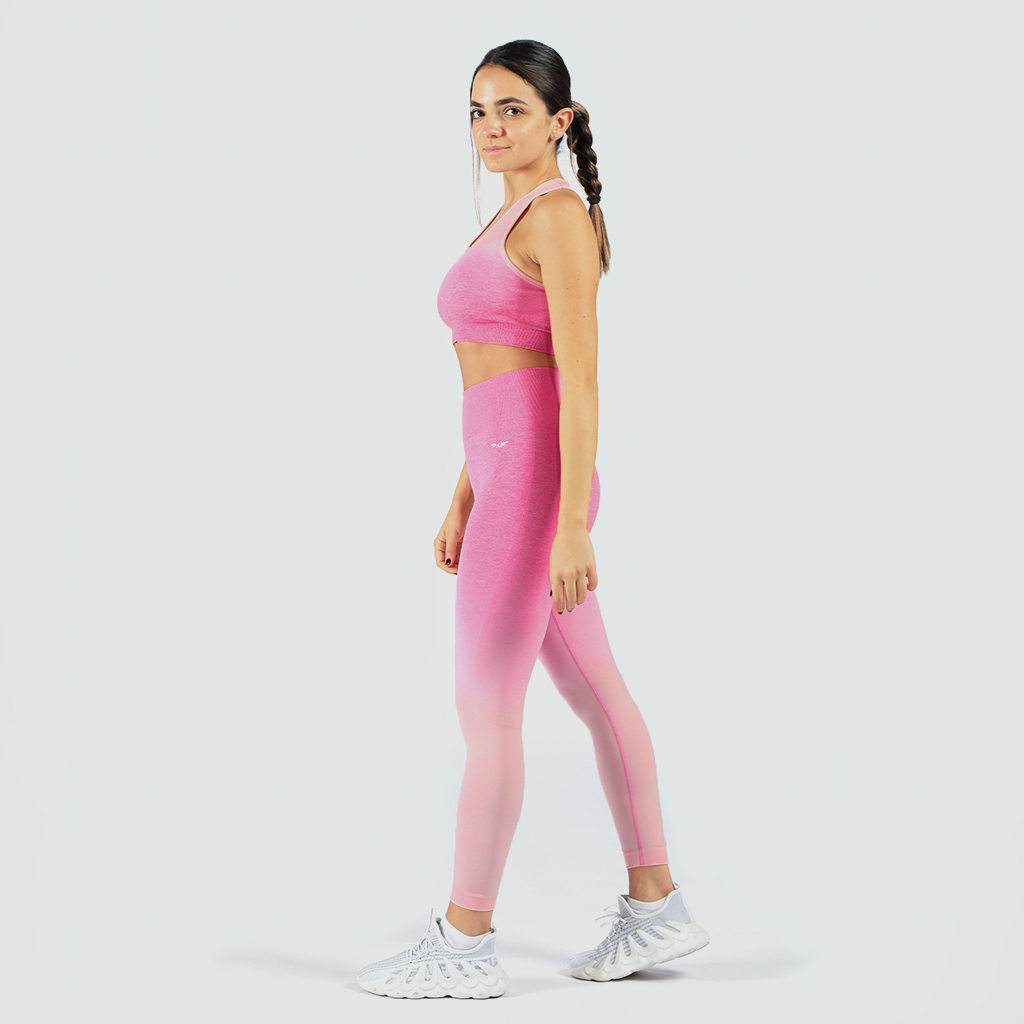  Woman looking at camera wearing matching bra and leggings with same pink color and logo
