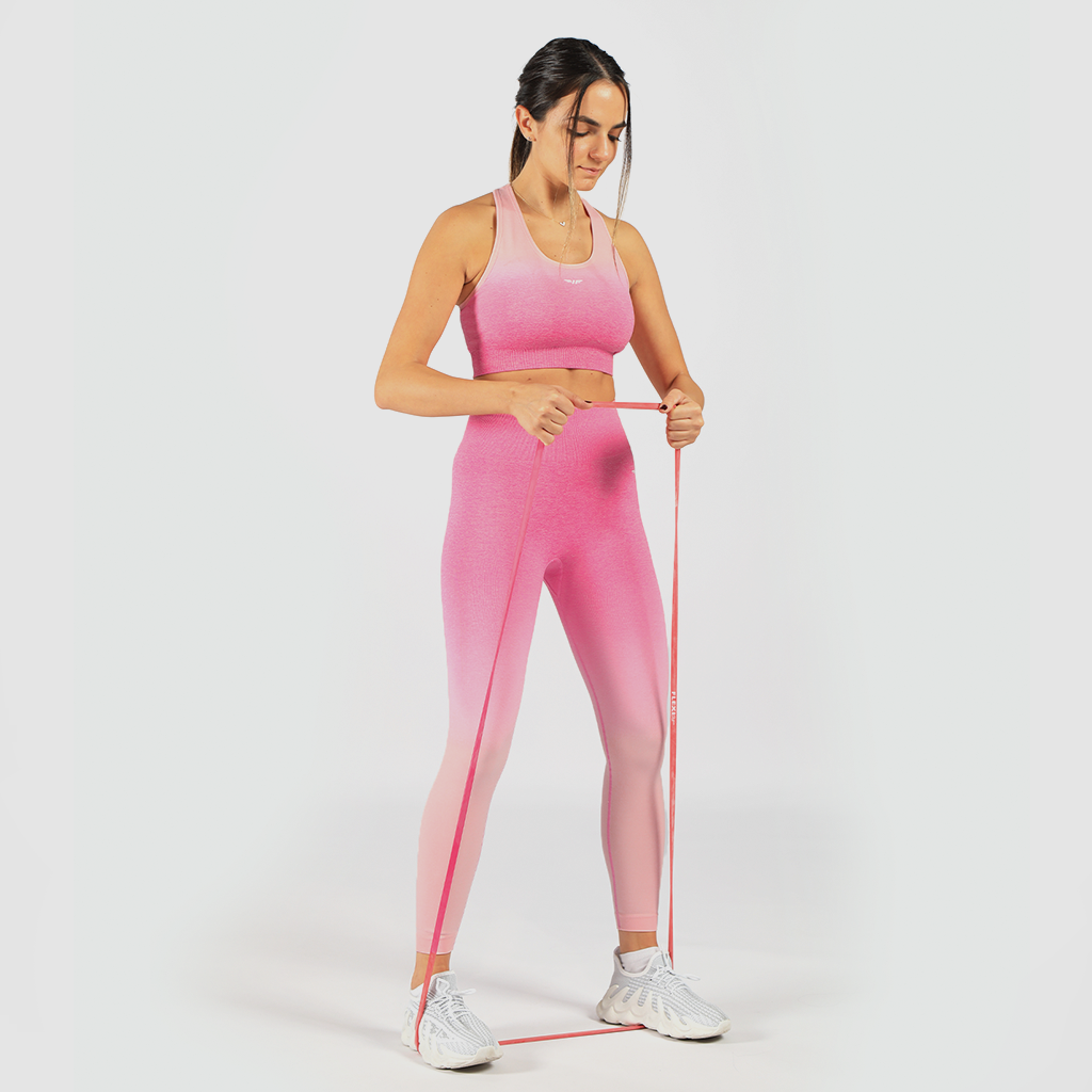 a fit woman stand with pose sports and look at down ,she wearing matching sport bra and legging pink ,shoes white 