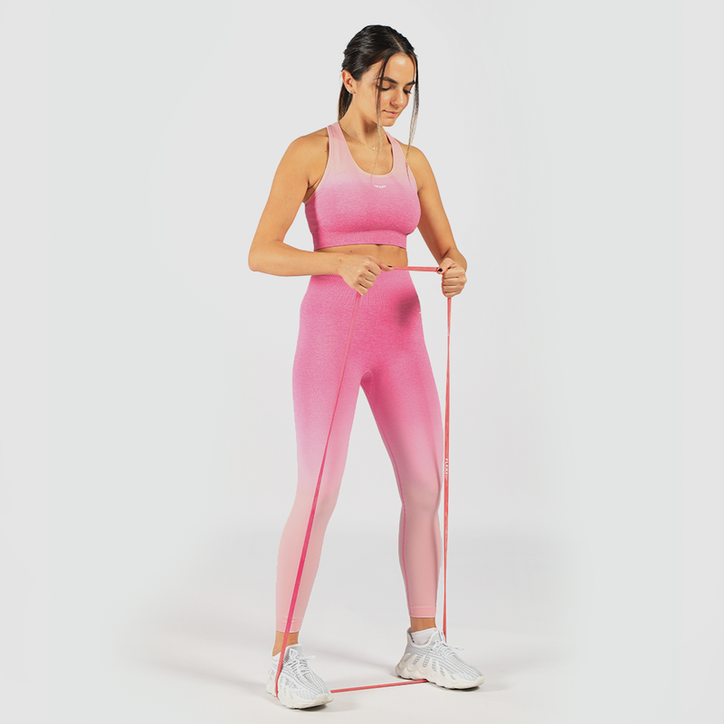 a fit woman stand with pose sports and look at down ,she wearing matching sport bra and legging pink ,shoes white 