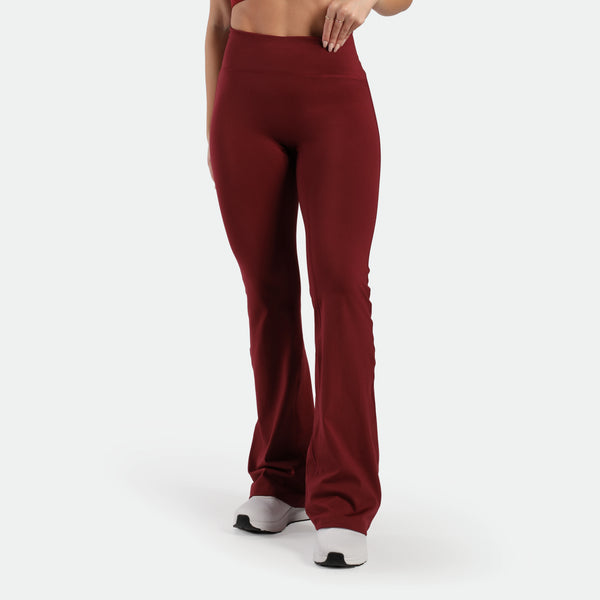 a fit woman wearing flared legging pomegranate red with shoes white  