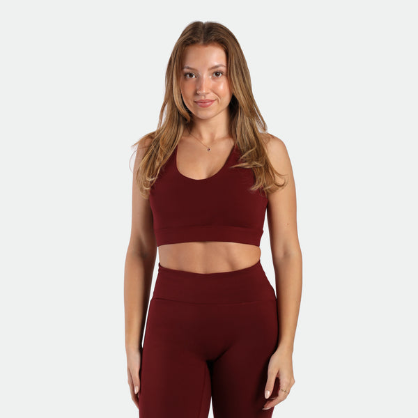 a fit woman wearing matching set bra and flared  legging pomegranate red 