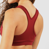 Back view of a woman wearing a red bra and tights, light gray background