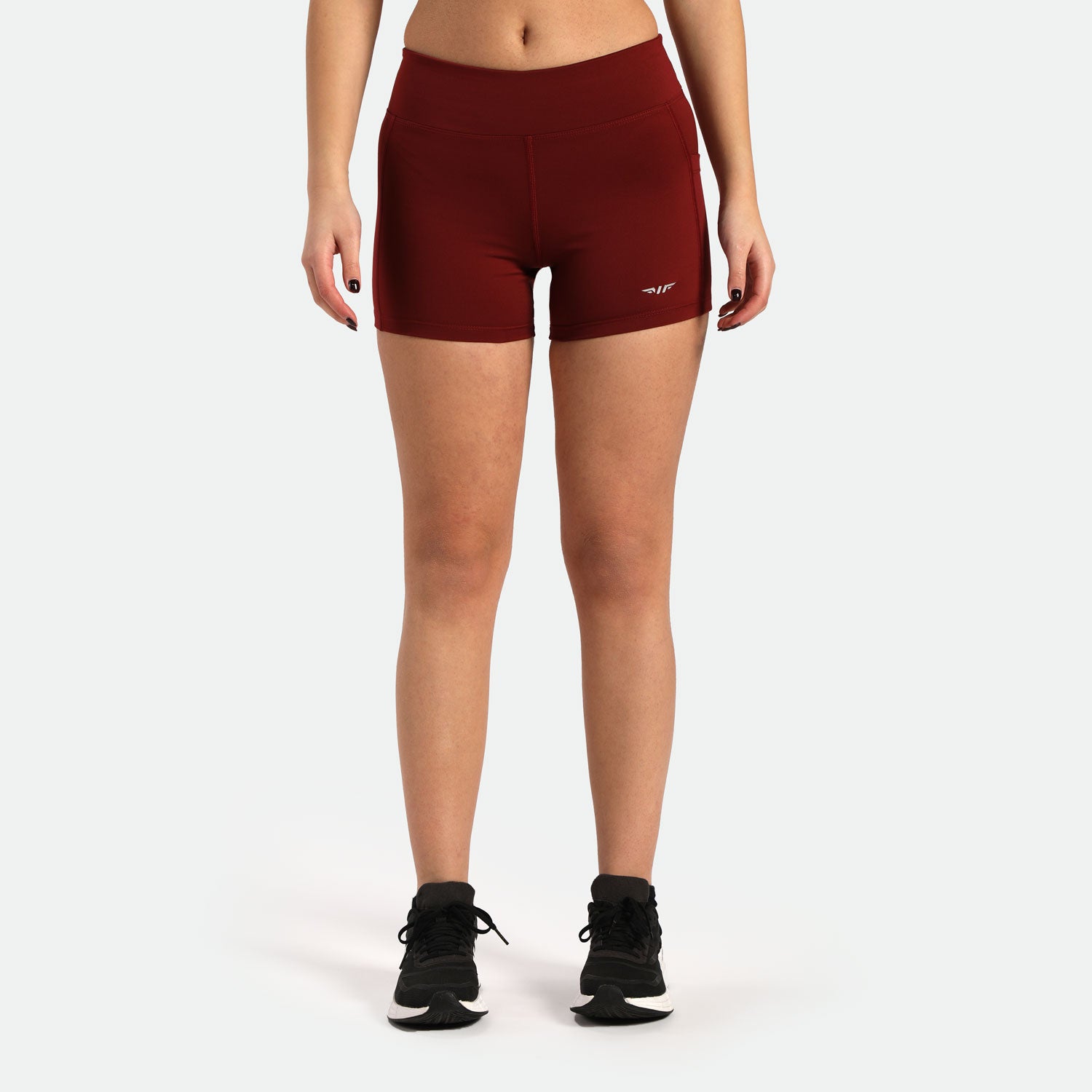 a fit woman wearing short red with logo and shoes black  plus the background is light grey 