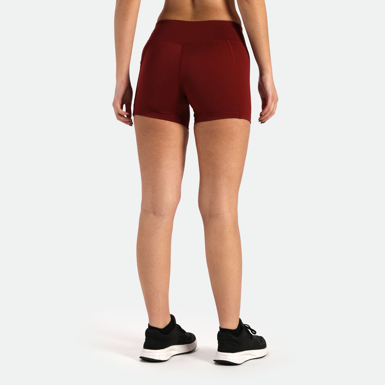 a back view for fit woman wearing short red with shoes black ,plus the background  is light grey 